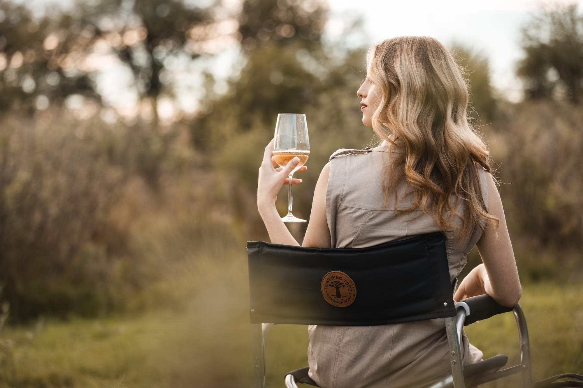 Woman relaxing in Towering Tree camping chair at golden hour